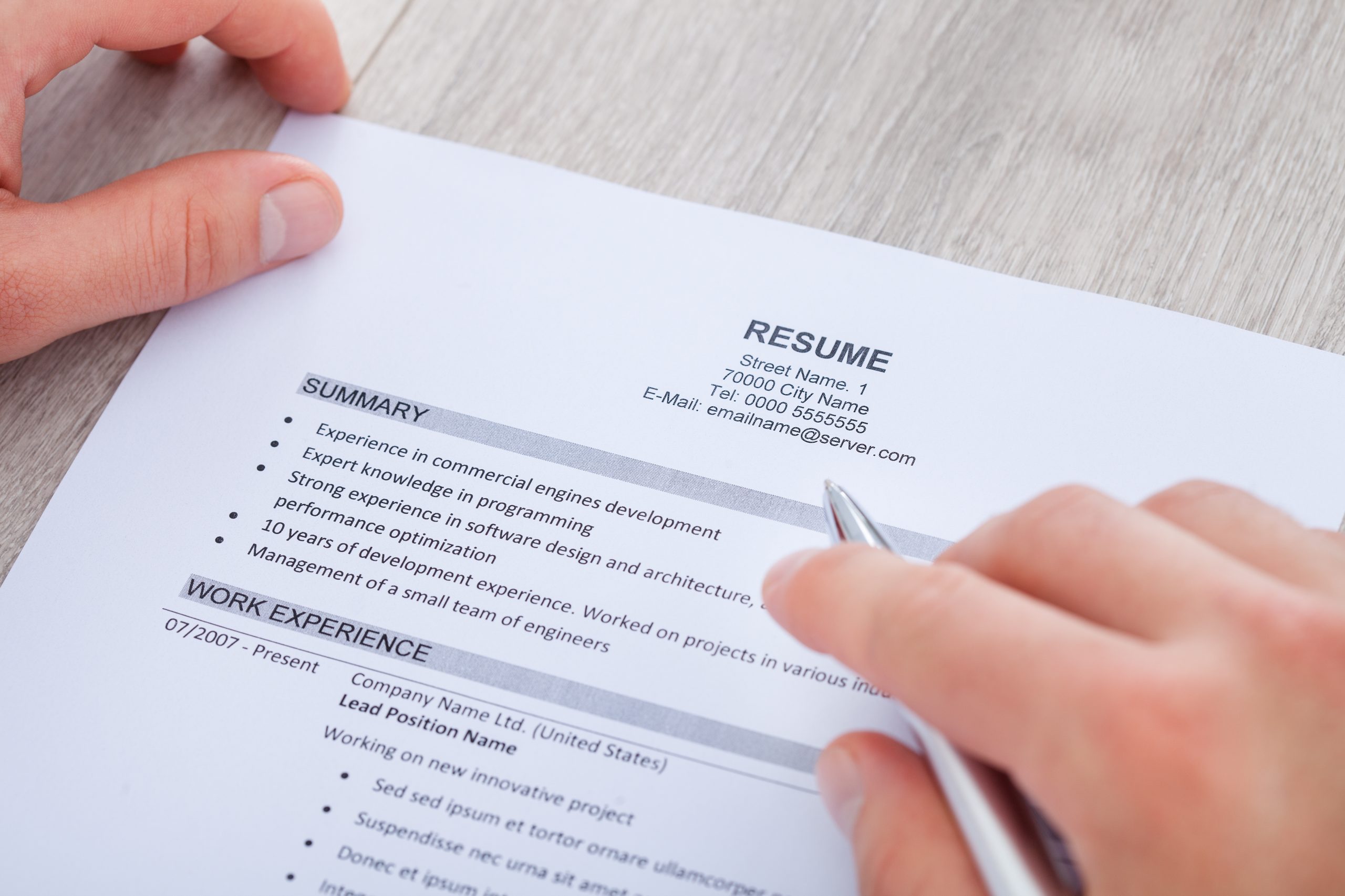 Close-up Of Businessman Reading Resume With Tea Cup On Desk
