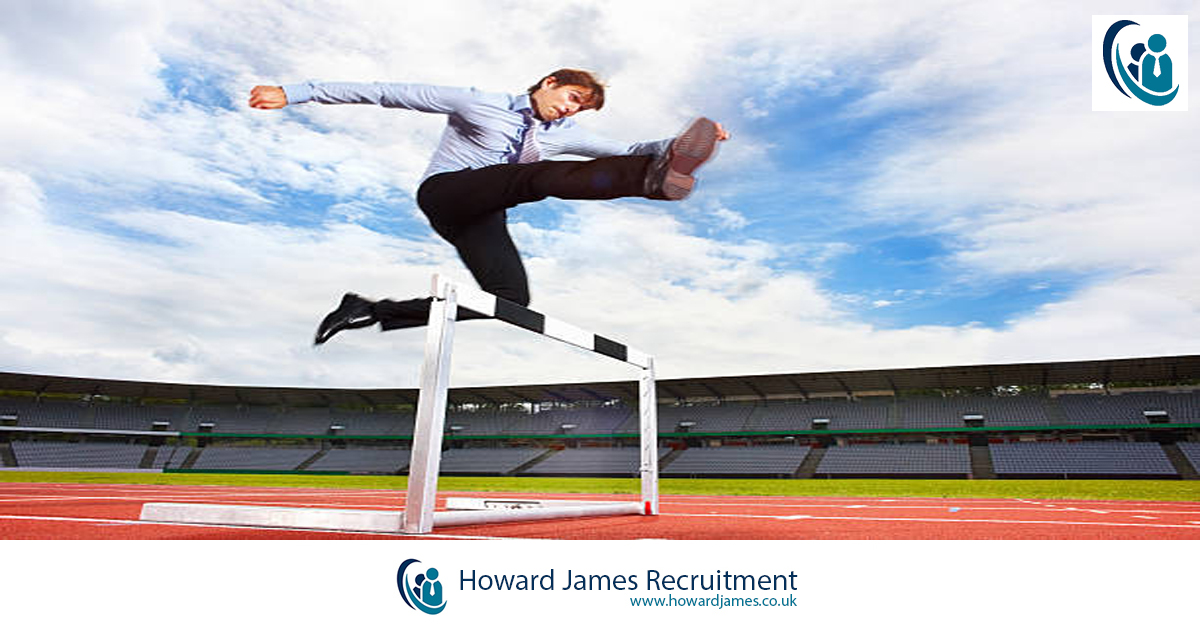 A businessperson jumping over hiring obstacles like hurdles on a racetrack.