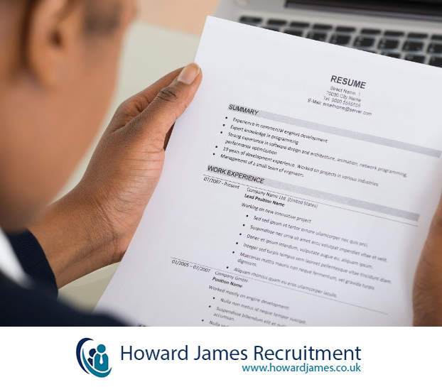 A recruiter happily reviewing CVs with a ticking clock beside them. A recruiter happily reviewing CVs with a ticking clock beside them.