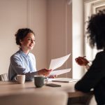 A friendly conversation during a business meeting in a well-lit modern office space, highlighting collaboration and teamwork.