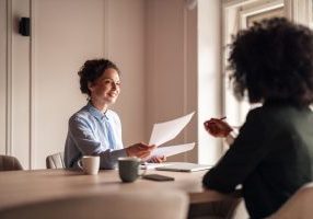 Professional Business Meeting Between Two People in a Modern Office Setting A friendly conversation during a business meeting in a well-lit modern office space, highlighting collaboration and teamwork.