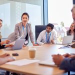 Businesswoman Leading Multi-Cultural Business Team Meeting And Collaborating Around Table In Office