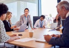Businesswoman Leading Multi-Cultural Business Team Meeting And Collaborating Around Table In Office