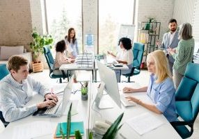 A busy office filled with professionals collaborating, working, and discussing projects, emphasizing teamwork and productivity in a stylish and well-lit environment.