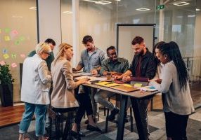 Cheerful diverse office people group talking and enjoying teamwork during staff meeting. Happy multiracial coworkers have fun working together at office brainstorming. Teamwork concept.