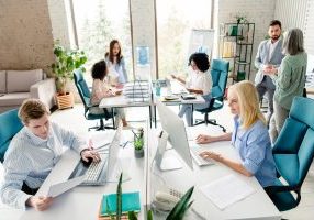Group of employees working in a contemporary office environment while engaging in teamwork, collaboration, and individual tasks under natural light in an organized and professional workspace.