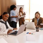 Multicultural office team collaborating on project. Woman using wheelchair works on tablet with colleagues. Concept of inclusion, accessibility, diversity and teamwork in modern business.