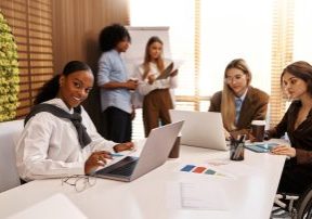 Multicultural office team collaborating on project. Woman using wheelchair works on tablet with colleagues. Concept of inclusion, accessibility, diversity and teamwork in modern business.