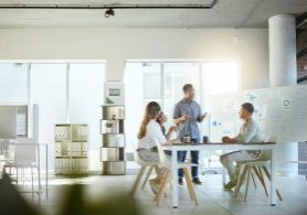 Group of diverse businesspeople having a meeting in an office at work. Young african american businessman talking while doing a presentation at a table for coworkers. Businesspeople planning together