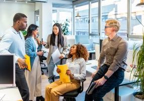 Multi-ethnic colleagues discussing project details, sharing ideas, and working together in a modern coworking office