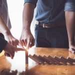 Business teamwork risk control concept, Business team protect wooden block fall to planning and strategy in risk to business Alternative and prevent. Investment Insurance Business.