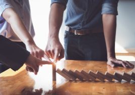 Business teamwork risk control concept, Business team protect wooden block fall to planning and strategy in risk to business Alternative and prevent. Investment Insurance Business.